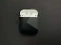 AirPods in einer schwarzen Hülle mit grauem geometrischem Muster.