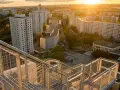 Blick von einer Treppe auf den Skywalk Marzahn bei Sonnenuntergang. Hohe Wohnhäuser und grüne Flächen prägen die Szenerie.