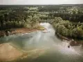 Malownicze jezioro Świętajno otoczone lasami i trzcinami. W oddali widać zabudowania.