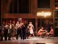 Scena z musicalu "1989". Aktorzy w strojach z epoki, neon "mięso" w tle.