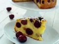 Una fetta di torta soffice e dorata, ricca di ciliegie succose, cosparsa di zucchero a velo. Perfetta per un momento di dolcezza.