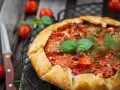 Torta salata con pomodorini freschi e basilico, pronta per essere gustata.