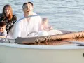 Famiglia felice su un barchino a Venezia, con bambini che guardano l'acqua.