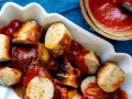 Leckere Currywurst mit einer würzigen Currywurst-Sauce und Currypulver bestreut, serviert in einer weißen Schale.