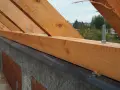 Murłata, czyli belka drewniana, mocowana do wieńca, stanowi podstawę konstrukcji dachu. Widać ją na tle nieba i drzew.
