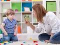 Mama karci synka za kłamstwo. Chłopiec ma smutną minę, a na dywanie leżą klocki.