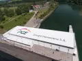 Widok z lotu ptaka na elektrownię wodną PGE Energia Odnawialna S.A. z charakterystycznym logo. Widać tam też helikoptery i samochody.
