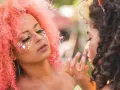 Kolorowy makijaż na festiwal z brokatem i kamyczkami. Różowe włosy i błyszczące oczy.