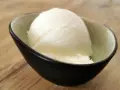 Ein Löffel cremiges Sorbet ohne Zucker in einer stilvollen Schale auf Holzhintergrund. Erfrischend und leicht.