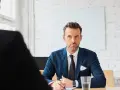 Mężczyzna w garniturze, prawdopodobnie headhunter, prowadzi rozmowę kwalifikacyjną.