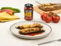 Dos calabacines rellenos de carne y gratinados con queso, servidos en un plato con tomate frito.