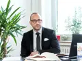 Ein Mann im Anzug sitzt am Schreibtisch, umgeben von Pflanzen. Er ist ein erfahrener Rechtsanwalt für Scheidungsrecht.