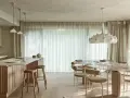 Nowoczesna kuchnia z wyspą i jadalnią. Wnętrze rozświetla designerska lampa wisząca, a całość dopełnia podwieszany sufit.