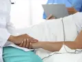 Lekarz w białym kitlu trzyma dłoń pacjenta, który leży w łóżku. To pokazuje, jaki lekarz nie może poślubić swojej pacjentki.