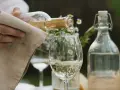 En hand häller upp vitt vin i ett glas. Den perfekta vitt vin temperatur är avgörande för smaken.