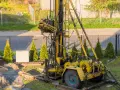 Żółta wiertnica na placu budowy. Rozpoczynają się prace nad studnią głębinową, koszt inwestycji zależy od wielu czynników.