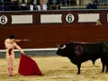 Zacięta walka torreadora z bykiem. Torreador w barwnym stroju, z czerwoną muletą i szpadą, staje naprzeciw krwawiącego, czarnego byka na piaskowej arenie.