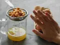 Kichererbsen im Sieb über Messbecher mit Aquafaba. Eier im Hintergrund. Perfekt für ei ersatz backen.
