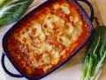 Piatto di verdure al forno con formaggio fuso, contornato da coste verdura fresche.