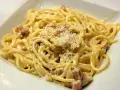 Pyszne spaghetti carbonara z kawałkami boczku, posypane parmezanem. Idealny wybór, jaki boczek do carbonary.