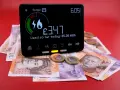 Cyfrowy licznik pokazuje £3.47 zużycia energii, a pod nim leżą banknoty i monety. To pokazuje realne ogrzewanie gazowe koszty.
