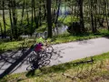 Dwie osoby na rowerach przemierzają malownicze bory tucholskie. Trasy rowerowe wiodą przez las, wzdłuż strumienia.
