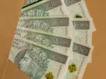 Stos banknotów 100 zł, idealnych na prezent, ile daje się na komunię?