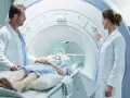 Pacjentka leży w skanerze MRI, podczas gdy lekarze przygotowują badanie. To właśnie mri co to za badanie, które pozwala zajrzeć do wnętrza ciała.
