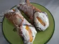 Dwa pyszne cannoli z kremem i kandyzowaną skórką pomarańczową, posypane cukrem pudrem. Ten makaron to prawdziwa rozkosz!