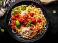 Talerz spaghetti z sosem pomidorowym, parmezanem i bazylią.