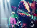 Koncertowe emocje! Gitarzysta gra na scenie, a w tle widać perkusistę. To jakby występ znanych zespołów muzycznych zagranicznych.