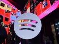 Duże logo Spotify na tle ekranów z podsumowaniami słuchania, w tym informacją o najpopularniejszym artyście na Spotify.