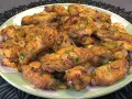 Alitas de pollo doradas con ajo y perejil en un plato verde.