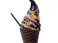 Schwarzes Eis in einer Waffel, bestreut mit bunten Streuseln. Ein schwarzer Löffel steckt darin.