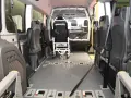 Innenraum eines Rollstuhlfahrzeugs, das als Taxi-Ersatz dient. Sitze und Rollstuhlhalterungen sind sichtbar.