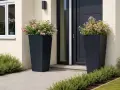 Zwei hohe, dunkle Pflanzkübel mit rosa und weißen Blüten schmücken den Eingangsbereich. Ein schöner Weg, den hauseingang zu bepflanzen.