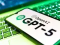 Ekran smartfona z logo OpenAI i napisem GPT-5 leży na podświetlanej zielonej klawiaturze.