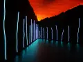 Installation lumineuse de Claude Lévêque, avec des néons bleus sur fond de ciel orangé et de montagnes sombres.