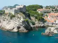 Widok na twierdzę Lovrijenac i miasto w Dalmacji Południowej. Kajaki pływają po turkusowej wodzie.