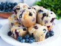 Wilgotne i puszyste muffinki z jagodami, polane lukrem. Idealne na śniadanie lub deser.