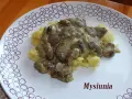 Sos z maślaków z koperkiem na purée ziemniaczanym na białym talerzu z wzorem kółek.