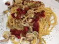Spaghetti con lupini e pomodorini secchi, un piatto di mare saporito e profumato, guarnito con prezzemolo tritato.