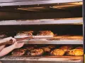 Bäcker lässt den **backofen spalt offen lassen beim backen** für knuspriges Brot. Mehrere Brote auf Regalen im Ofen.