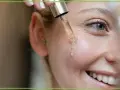 Kropla serum z **retinolem** spływa na policzek, obiecując odmłodzenie i wygładzenie skóry.