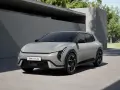 Nowoczesny, jasnoszary Kia EV4 GT-Line stoi na podjeździe przed minimalistycznym budynkiem.