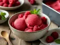 Himbeersorbet, das man einfach **sorbet selber machen ohne eismaschine** kann. Serviert in einer Schale mit frischen Himbeeren und Minze.