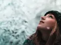 Junge Frau blickt in den Schnee, ihre Wangen gerötet, ein Zeichen von trockene Haut im Winter.