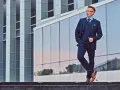 Elegancki mężczyzna w granatowym garniturze i kamizelce, z brązowymi butami. Idealne połączenie, jeśli zastanawiasz się, jakie buty do niebieskiego garnituru.