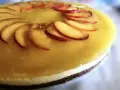 Cheesecake alla pesca con fette di pesca fresca disposte a raggiera sulla glassa gialla.