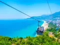 Kolejka linowa nad turkusowym morzem i plażą w Alanyi. Widok z góry na miasto i wybrzeże. Czy Alanya jest bezpieczna? Tak, wygląda na spokojną i piękną.